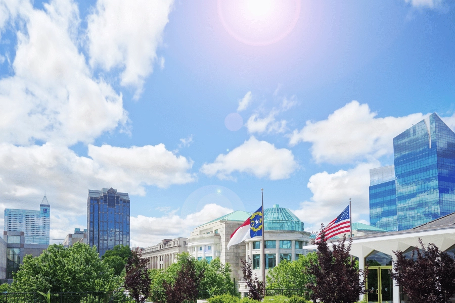 Raleigh, NC skyline on a sunny day with NC flag and US flag waving in the wind